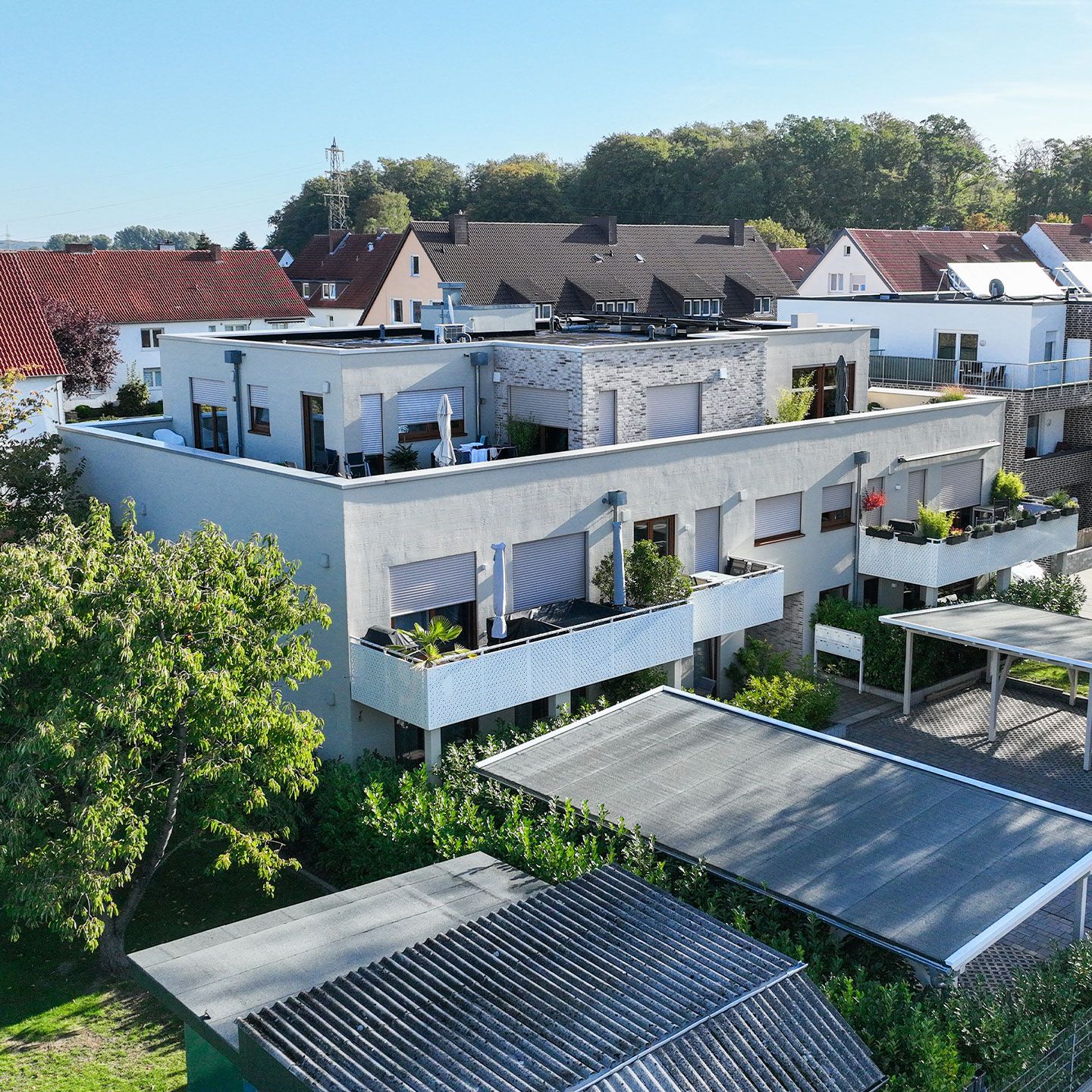 Moderne Wohngegend mit hellen Mehrfamilienhäusern, Balkonen und viel Grün in ruhiger Atmosphäre.