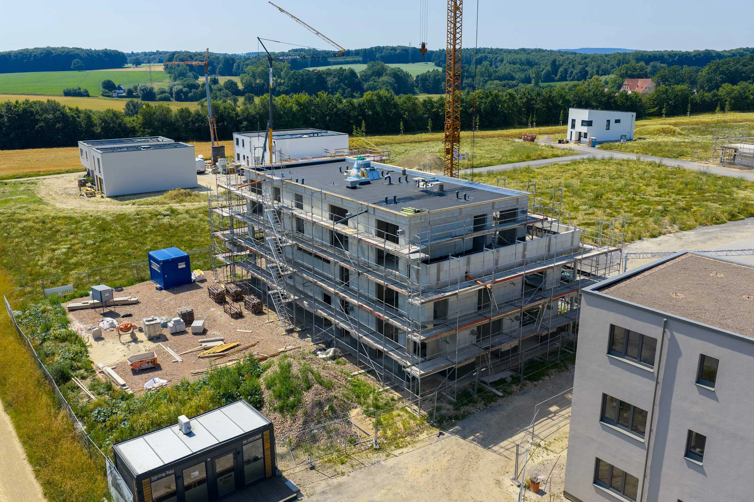 Eine ruhige Baustelle in ländlicher Umgebung mit einem mehrstöckigen Gebäude im Bau und einem Kran.