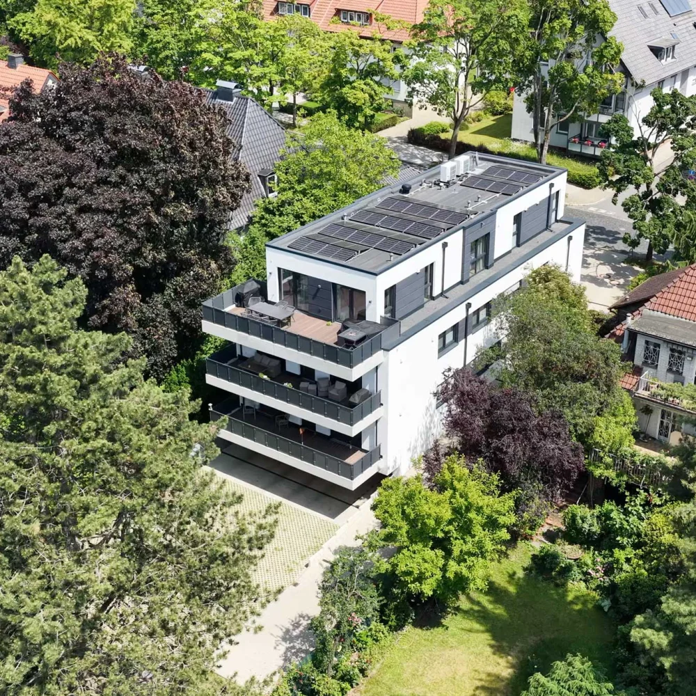 Vogelperspektive auf eine Wohngegend mit modernen und traditionellen Häusern, umgeben von viel Grün.