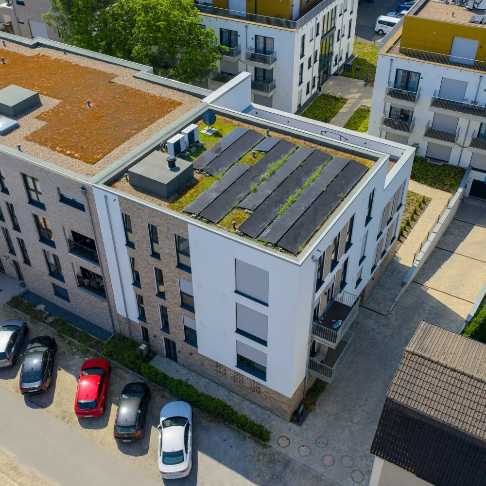 Moderne Wohngegend aus der Vogelperspektive mit begrünten Dächern und Solarpaneelen.
