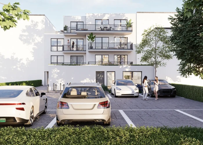 Moderne Wohnanlage mit geparkten Autos und zwei Personen im Gespräch, umgeben von grüner Natur.